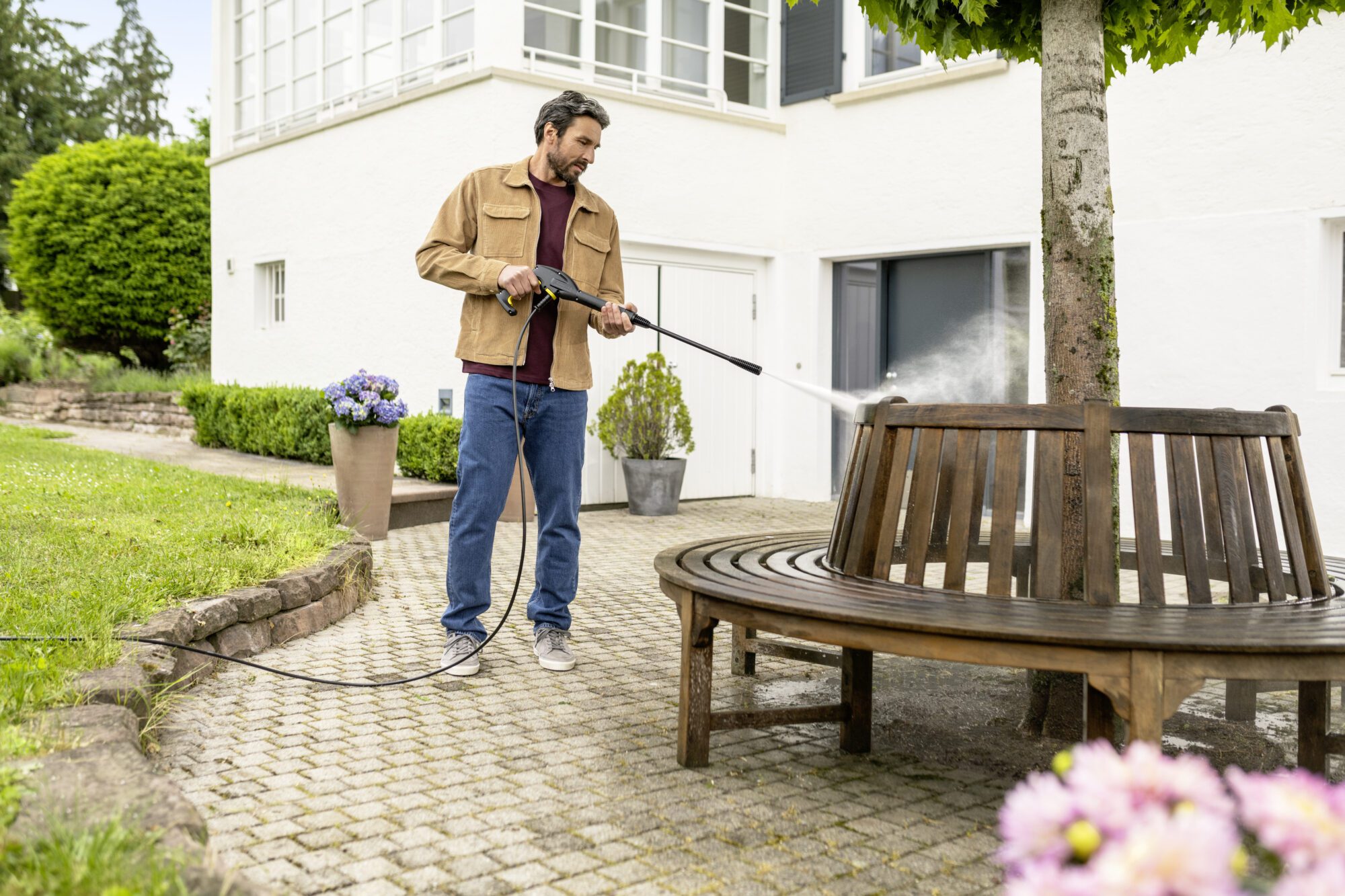 man using pressure washer in back yard